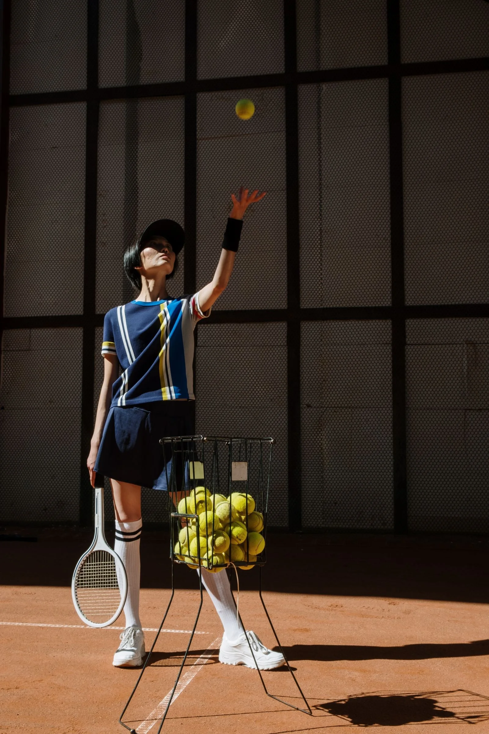 Jeune joueuse à l’initiation, panier de balles à côté